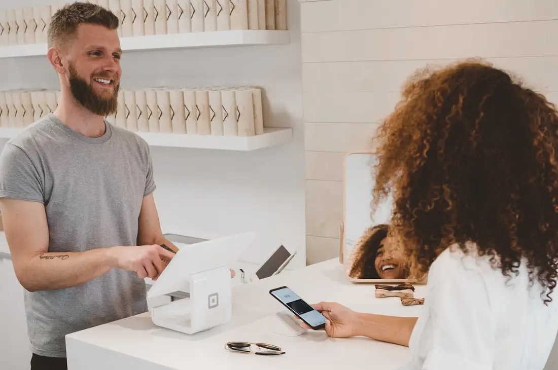 Clienta pagando en el mostrador de una tienda mostrando su teléfono